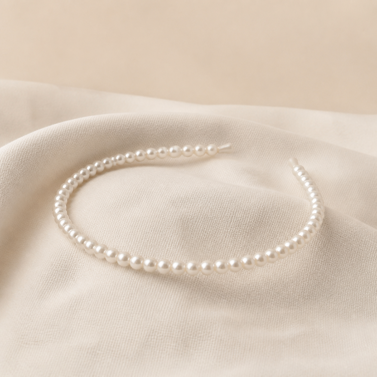 Serre-tête fin à perles posé sur tissu crème — Slim pearl headband on cream fabric