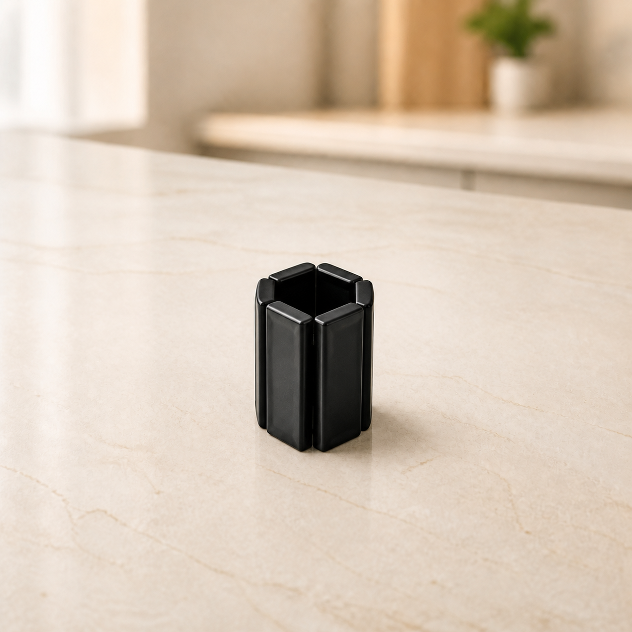 Dessous-de-plat pliable noir en position repliee — Black foldable trivet in compact folded position